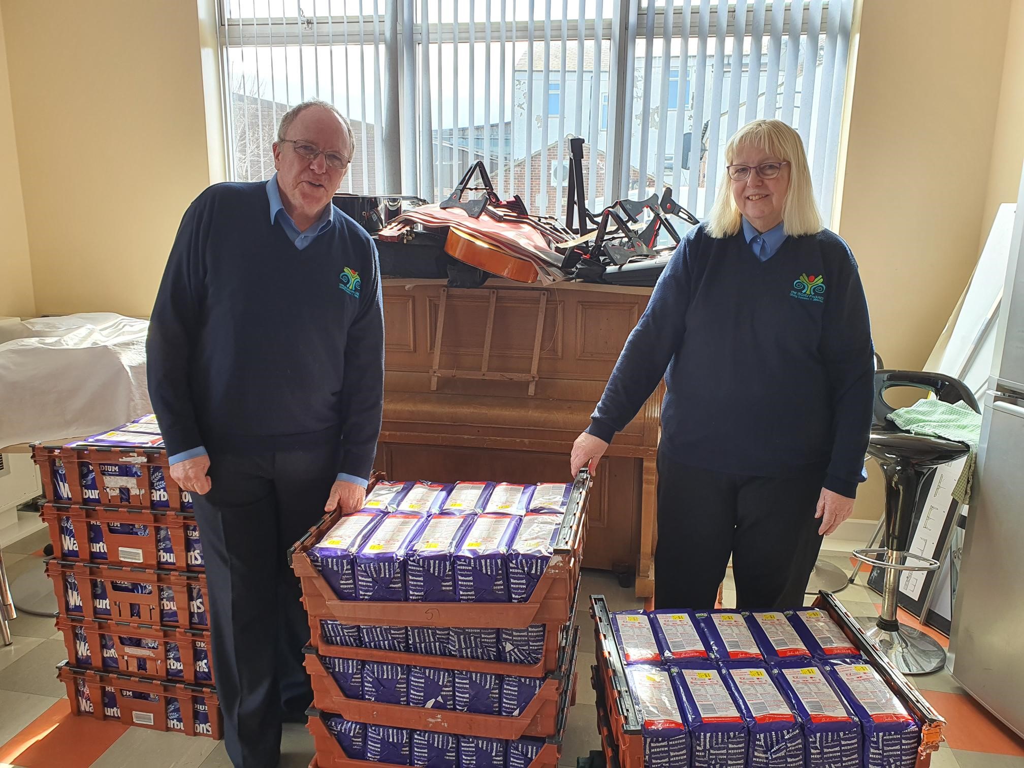 Image of Brian Jones, CEO of The Moses Project with wife Stella and pallets of food