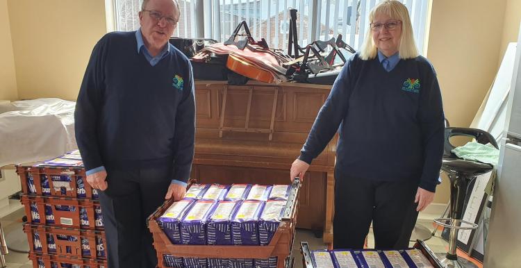 Image of Brian Jones, CEO of The Moses Project with wife Stella and pallets of food