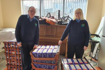 Image of Brian Jones, CEO of The Moses Project with wife Stella and pallets of food