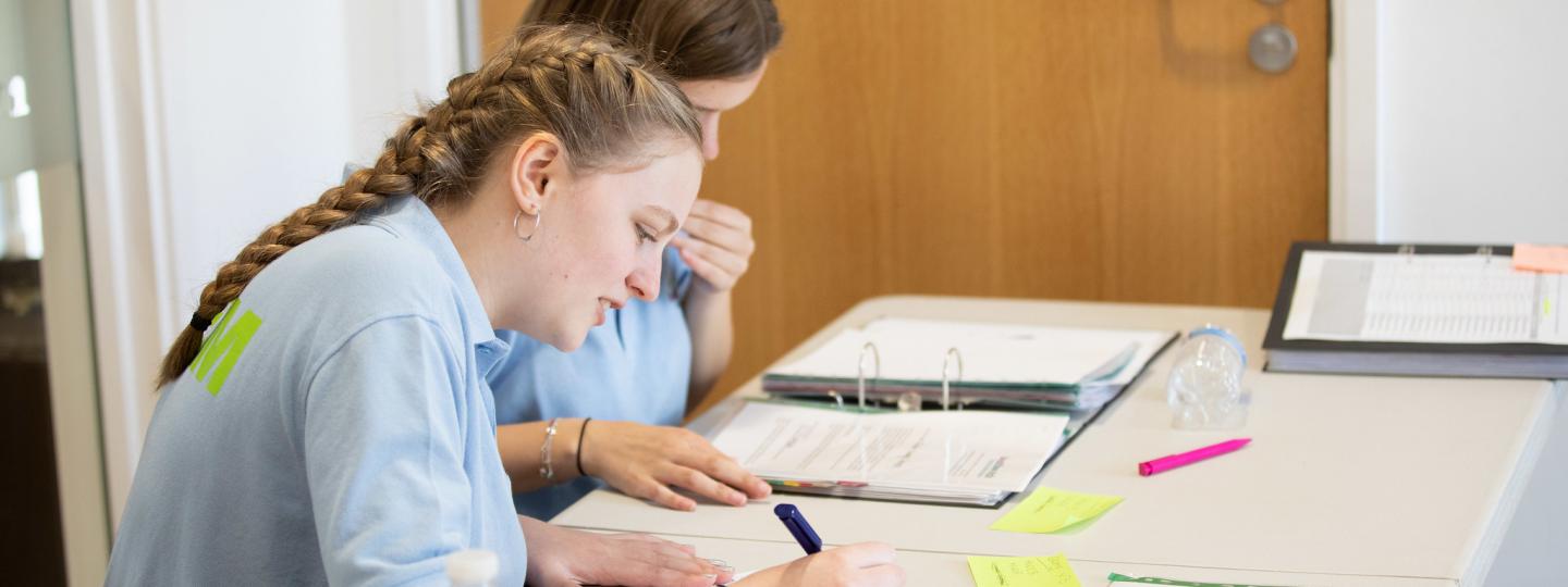 Two young Healthwatch volunteers sitting at a desk completing paperwork